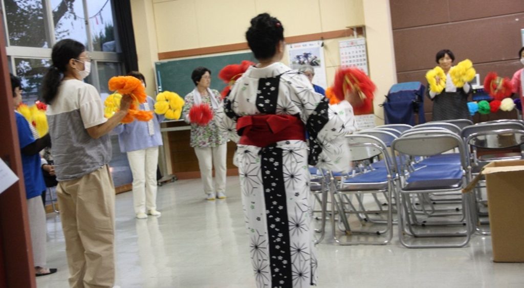 ホールの中で花を持って踊る女性たち